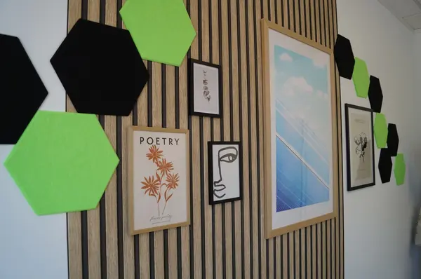 Moderne Wanddekoration mit grünen und schwarzen Filz-Sechsecken und gerahmten Bildern.