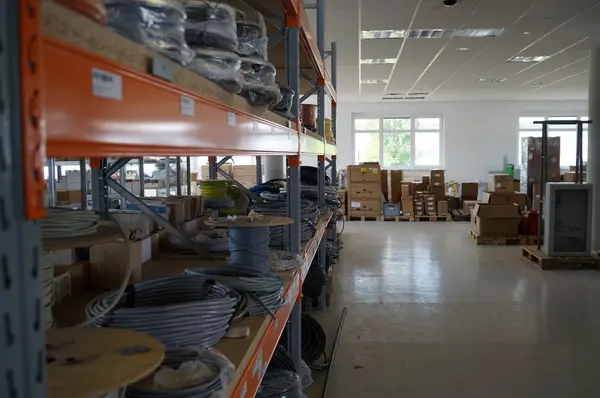 Lagerhalle mit Regalen voller Kabelrollen und Kartons für Elektroinstallation und Handwerk.