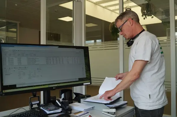 Mann arbeitet im modernen Büro am Computer und prüft Dokumente auf dem Schreibtisch.