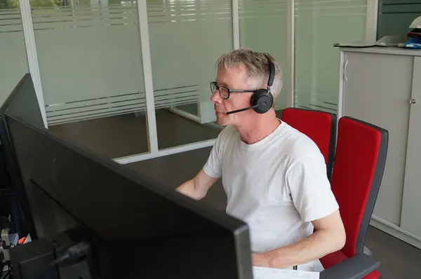 Mitarbeiter mit Headset arbeitet am Computer im modernen Büro für Kundenservice.
