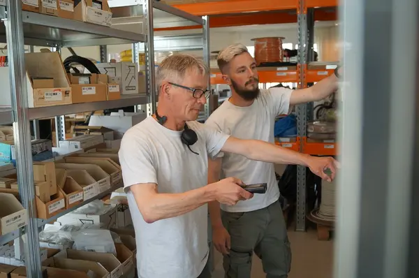 Zwei Mitarbeiter im Lager prüfen Warenbestände an Regalen mit elektronischem Scanner.