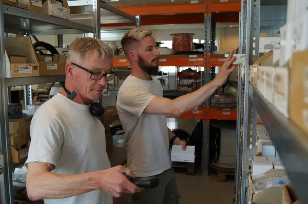 Zwei Männer sortieren Waren im Lager und scannen Kartons für die Inventur.